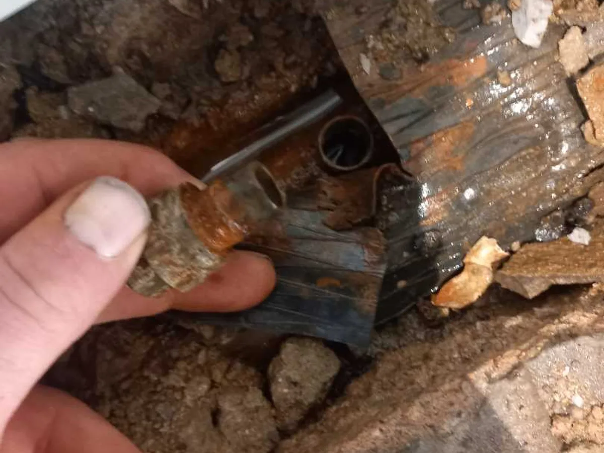 leak exposed at corroded soldered copper fitting beneath excavated concrete floor — leak located at