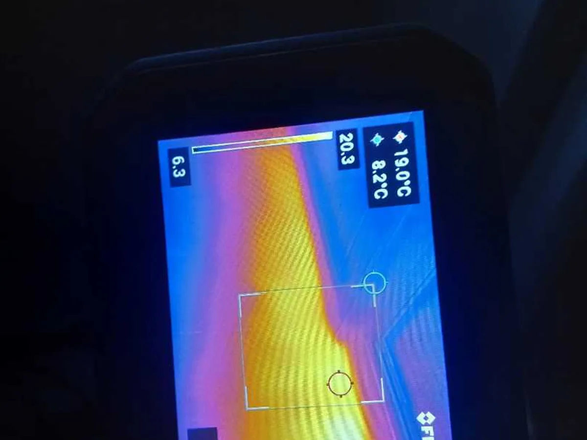 thermal imaging camera screen showing heat anomaly beneath floor during leak detection