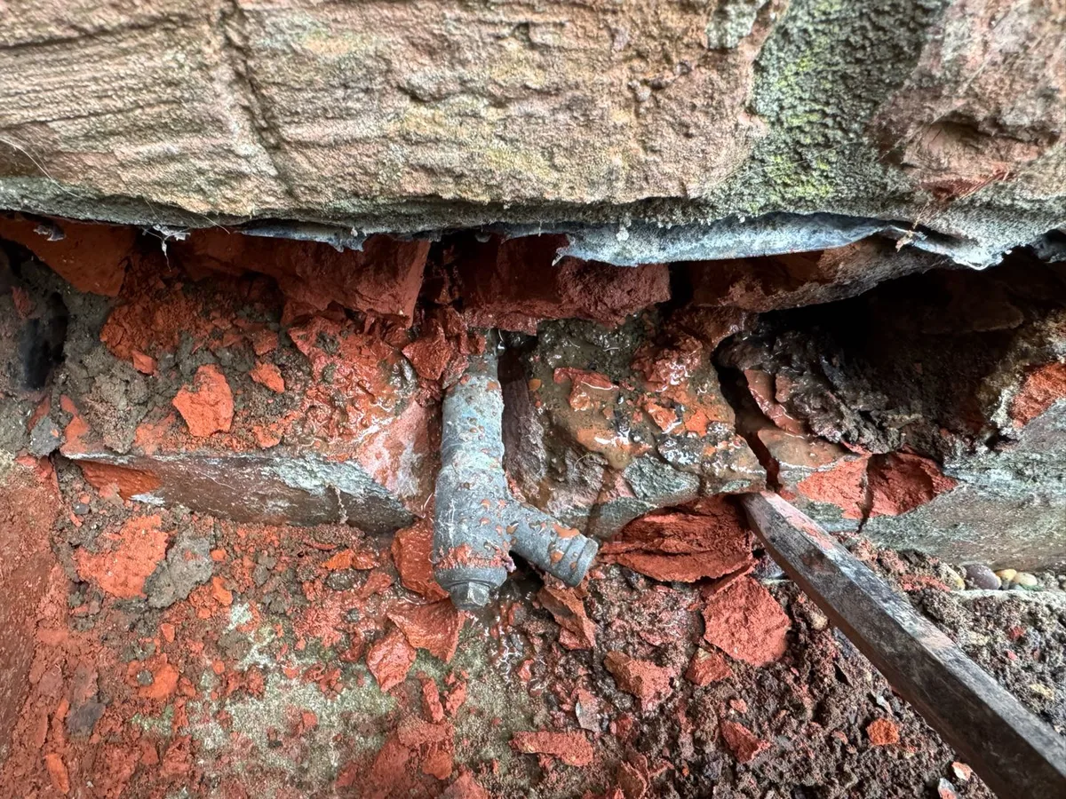 fault exposed at corroded heating pipe with pinholes in excavated external brickwork