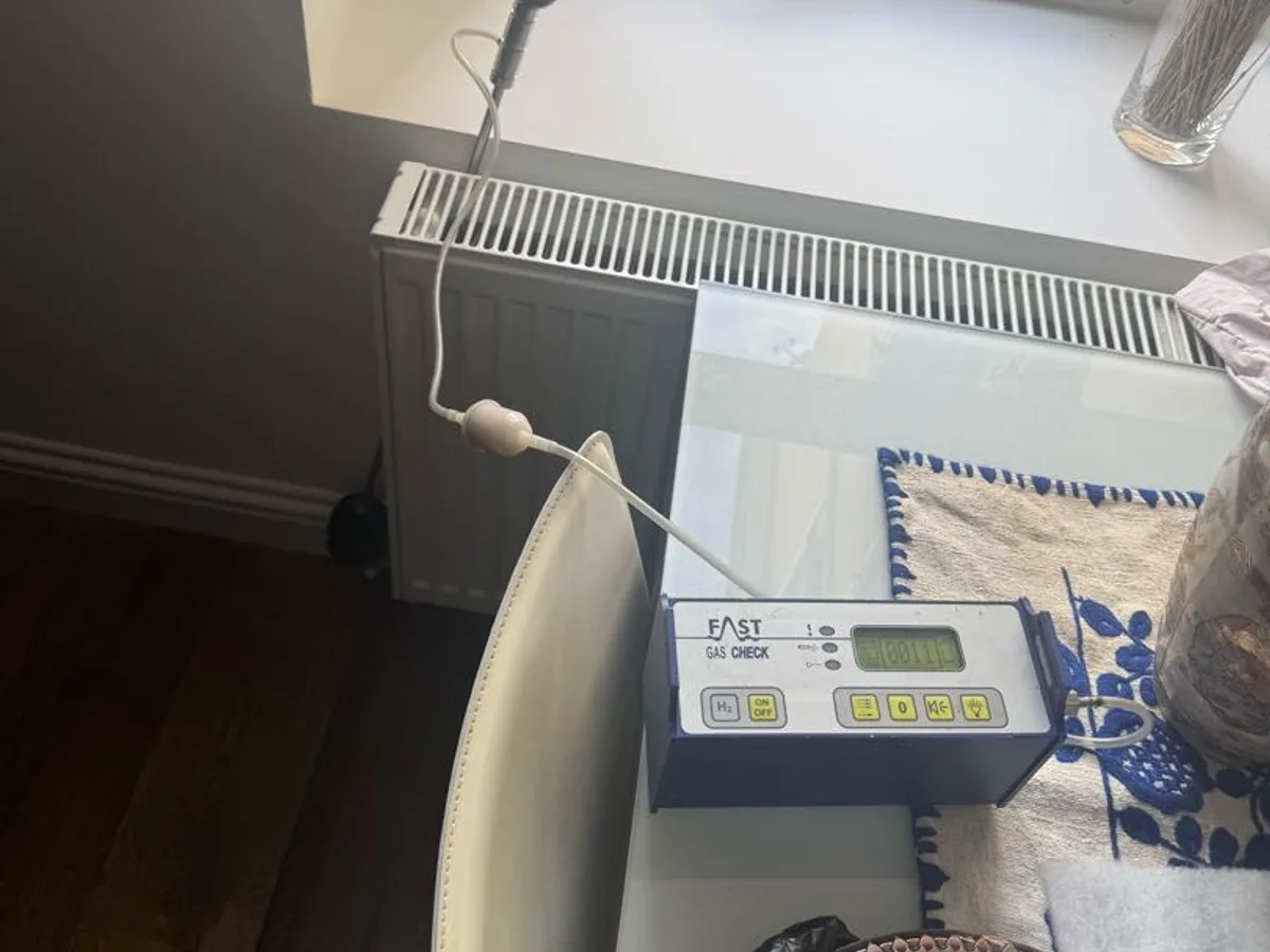 tracer gas analyser probe placed near lounge radiator pipework during leak detection