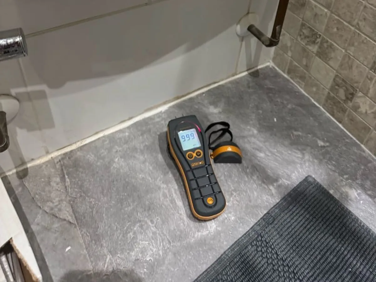 moisture meter on bathroom floor beside towel rail during leak detection survey