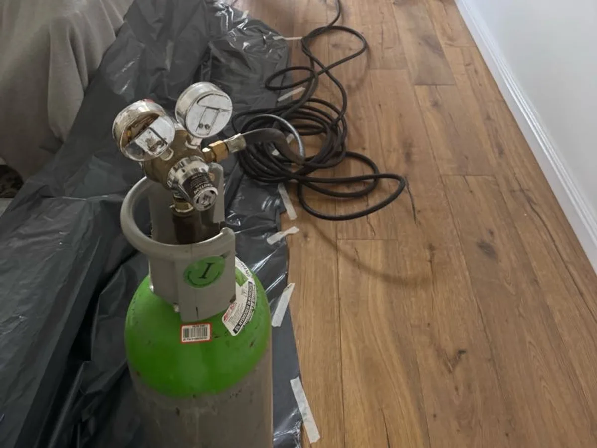 tracer gas cylinder with regulator connected to heating system in lounge during leak detection