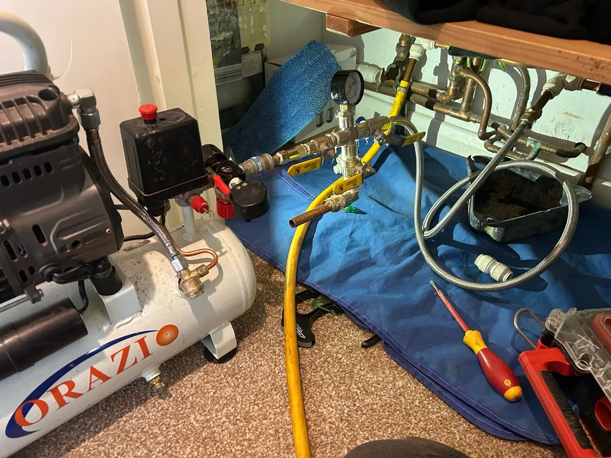 air compressor and manifold connected to heating system pipework during pressure test investigation — during leak detection