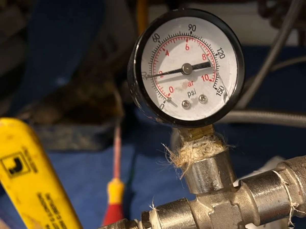 pressure gauge showing approximately two bar on heating system manifold during leak detection