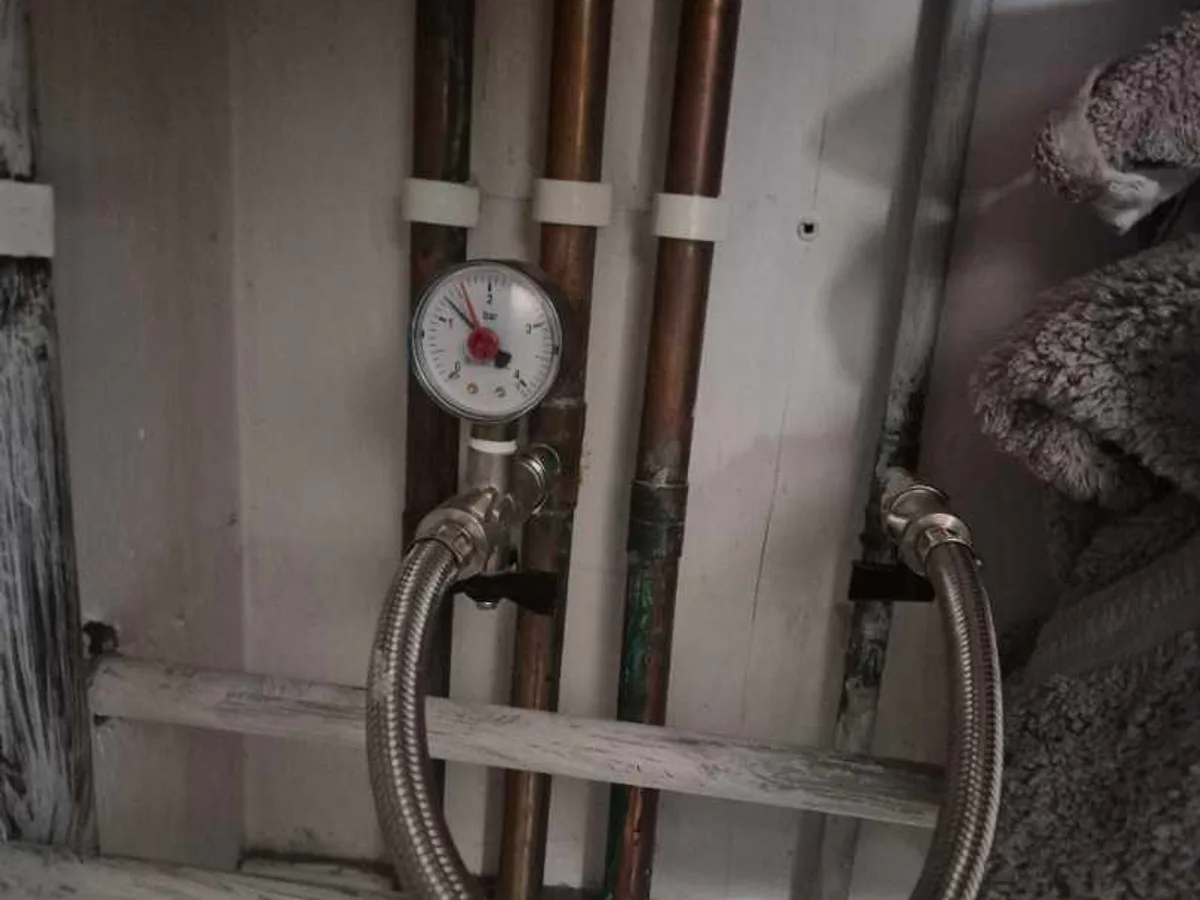pressure gauge connected to copper heating pipework in loft space during leak detection