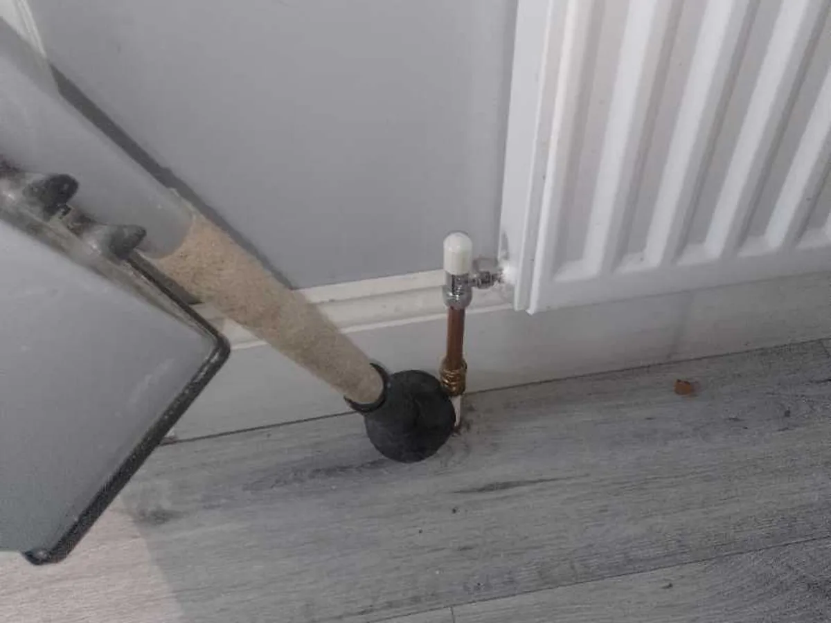 hallway radiator valve and copper pipe entry point through floor being tested during investigation — during leak detection