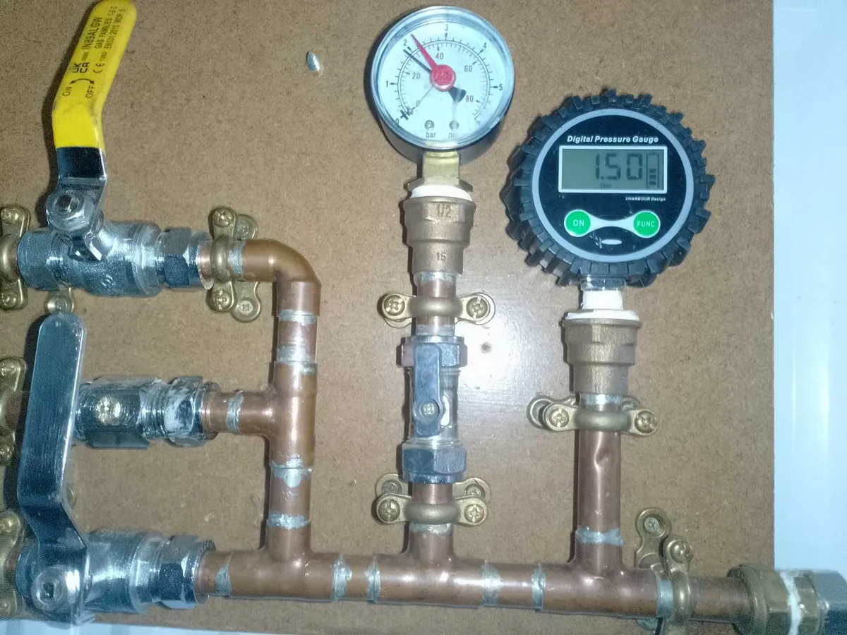 digital and analogue pressure gauges reading 1.5 bar on heating system manifold during leak detection