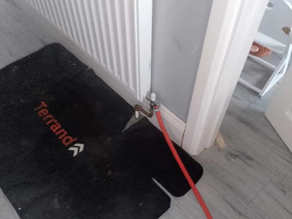 tracer gas hose connected to hallway radiator valve during leak detection survey