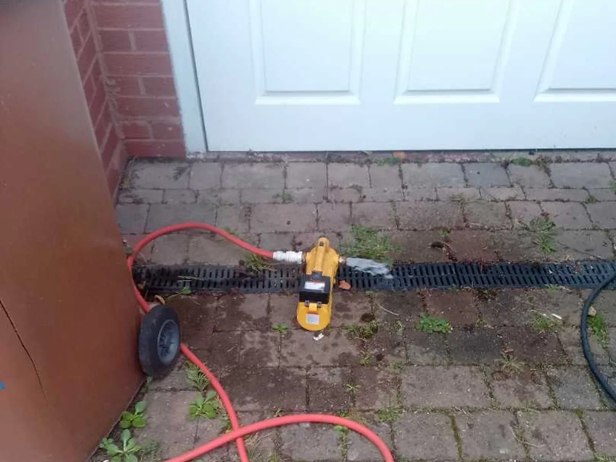 tracer gas injection unit connected via red hose on block-paved driveway during leak detection