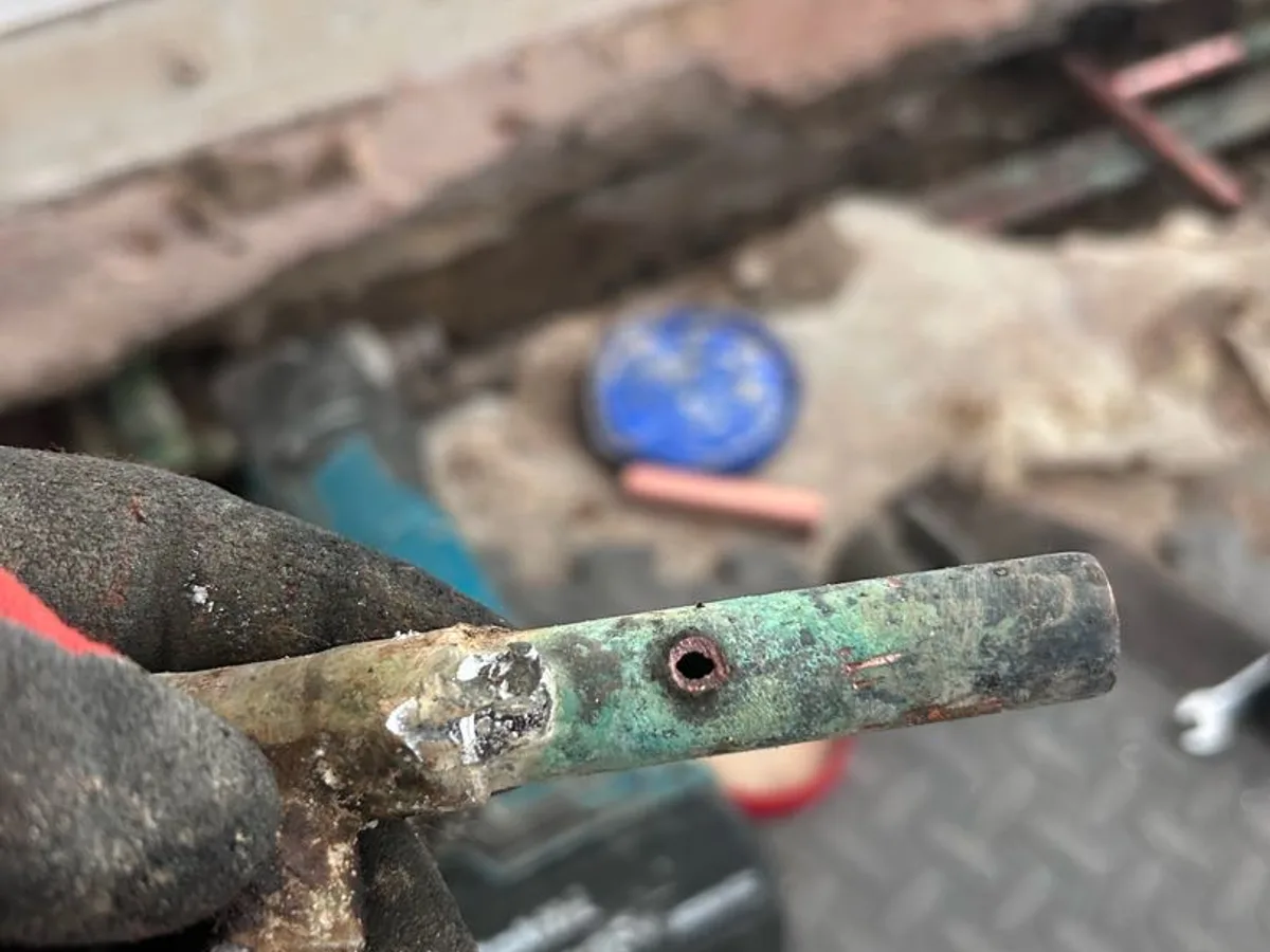 new copper pipe section installed in concrete floor trench as repair completed