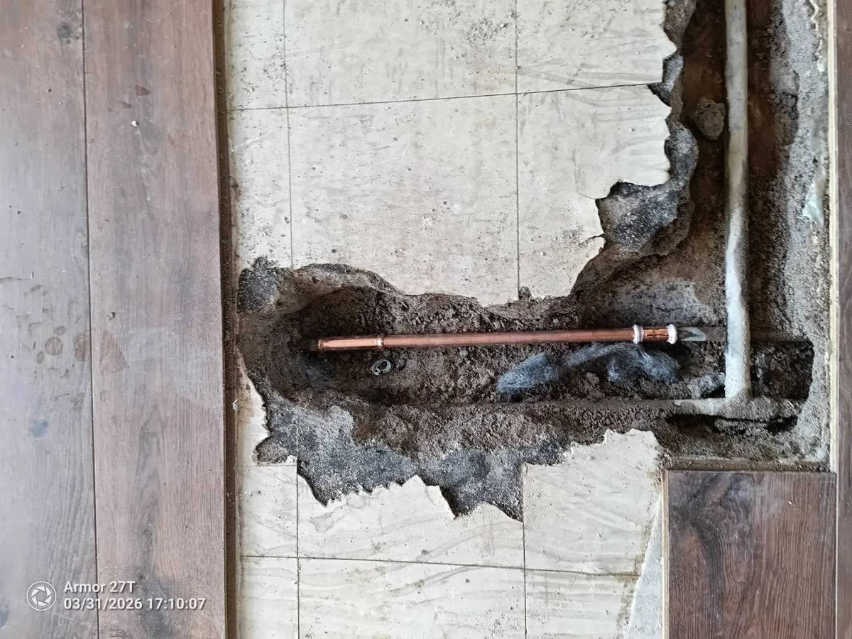 press-fit coupling installed on copper pipe in living room floor trench with repair in progress