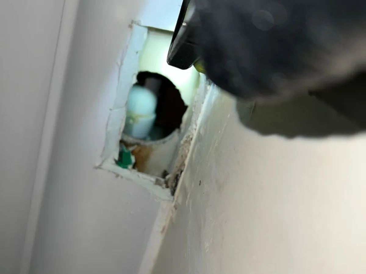 leak located at small access hole in kitchen ceiling with green tracer dye visible on waste fitting