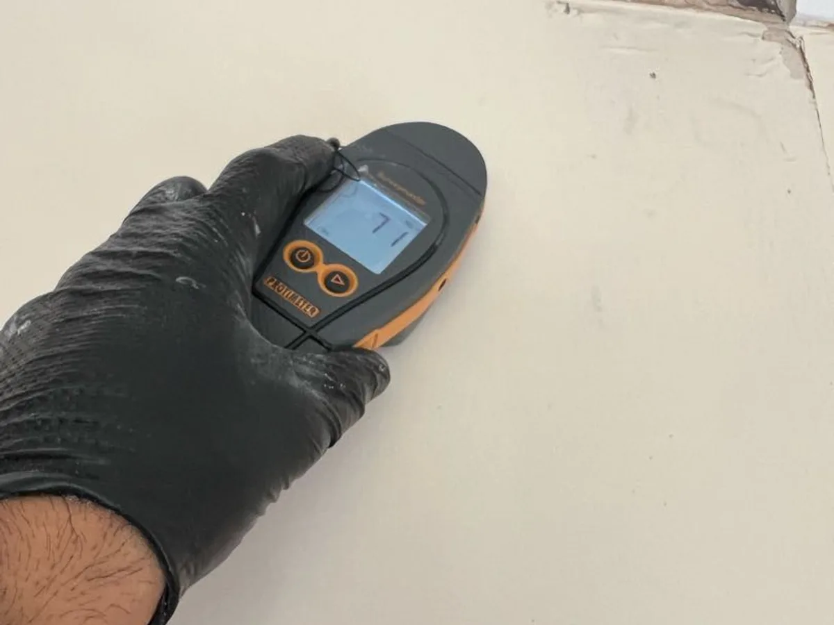 moisture meter reading on damp kitchen ceiling during leak detection investigation