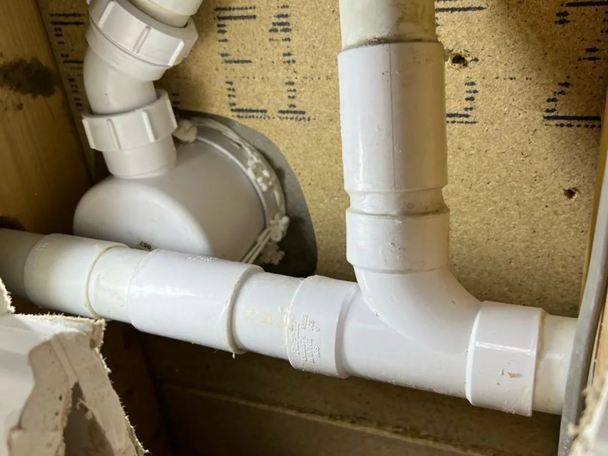 new waste pipe section and fittings installed as repair completed through ceiling access panel