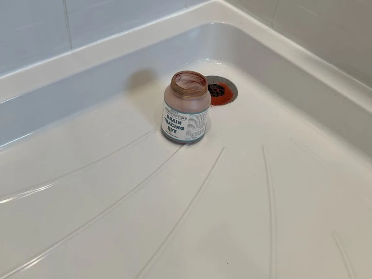 drain tracing dye jar placed at shower waste trap during leak detection