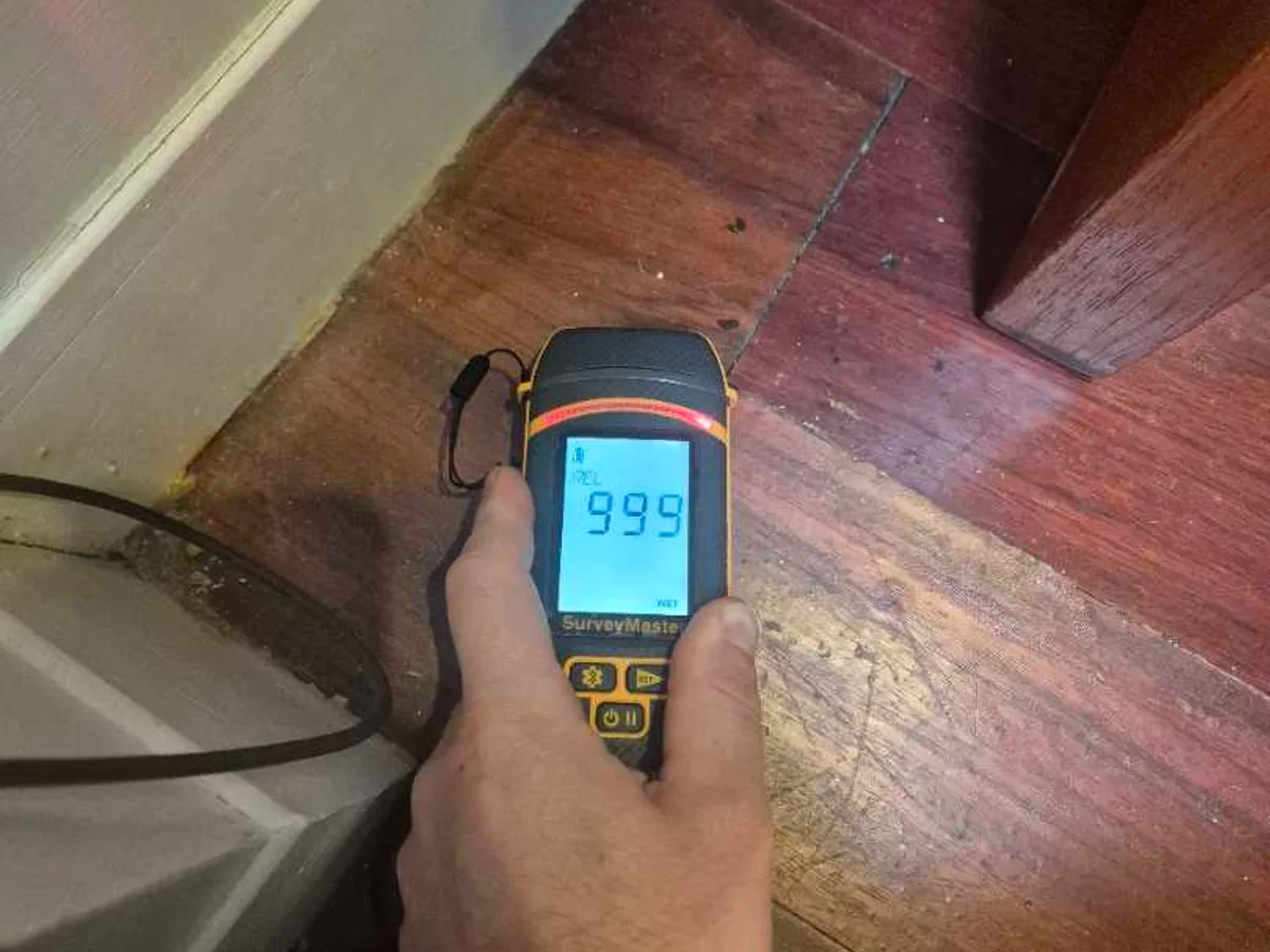 moisture meter reading 999 on utility room timber floor during leak detection