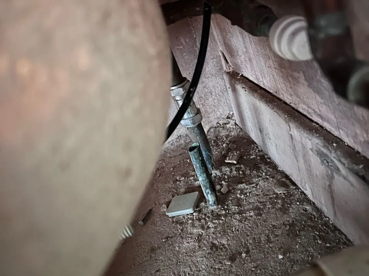 leak located at corroded old hot water pipe stub in subfloor void beneath bathroom
