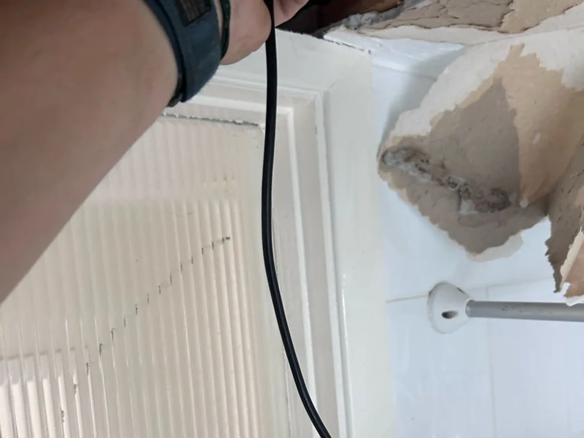 engineer feeding gas detector probe into ceiling void during leak detection