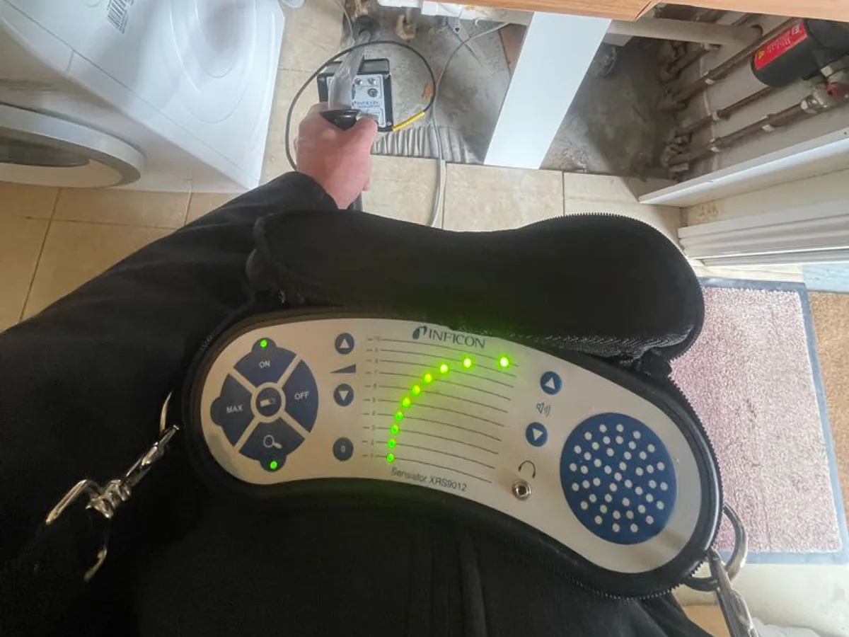 electronic gas detector in use beneath utility room worktop during tracer gas investigation — during leak detection