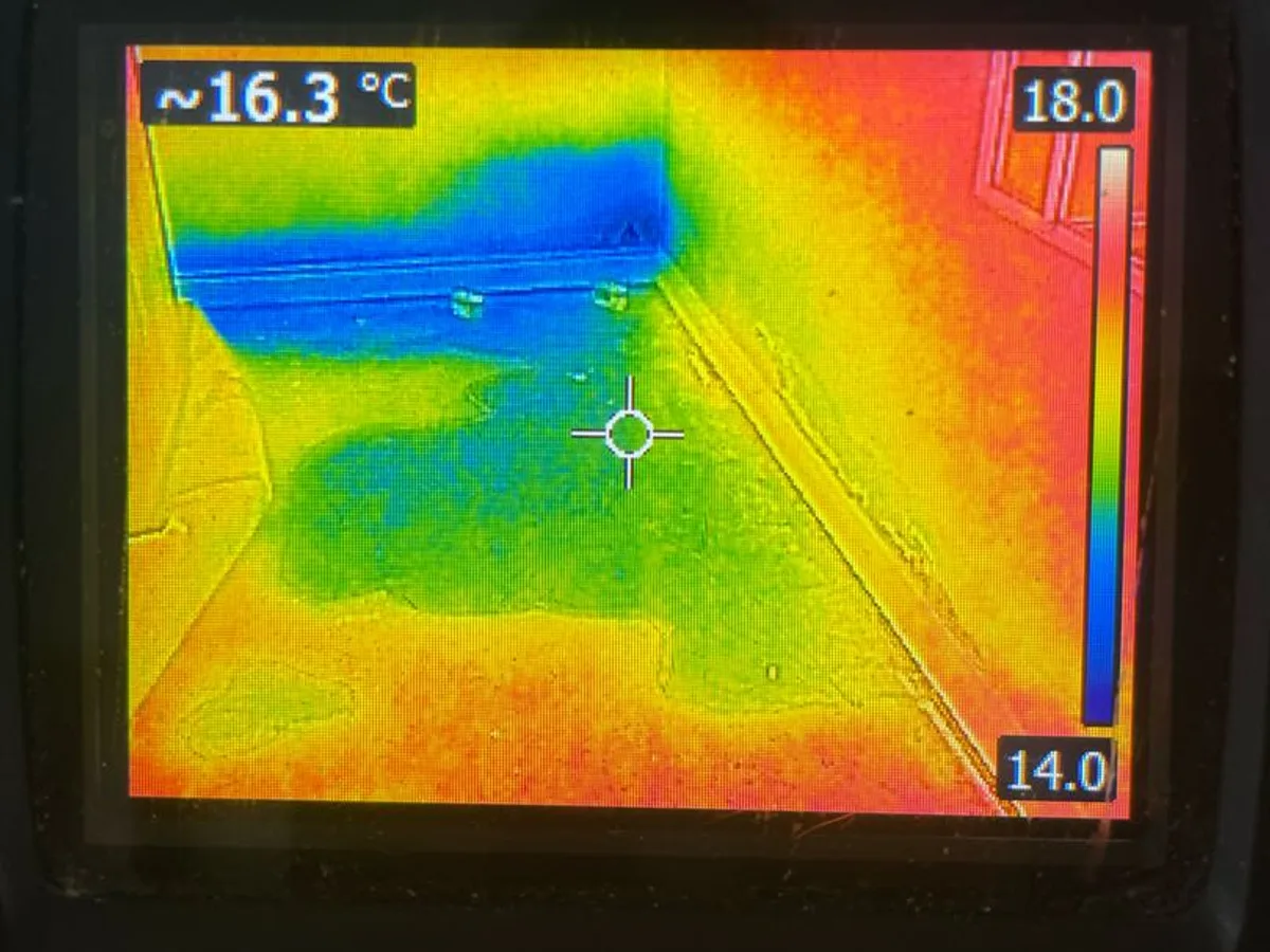 thermal imaging camera screen showing cold moisture anomaly on concrete floor during leak detection survey