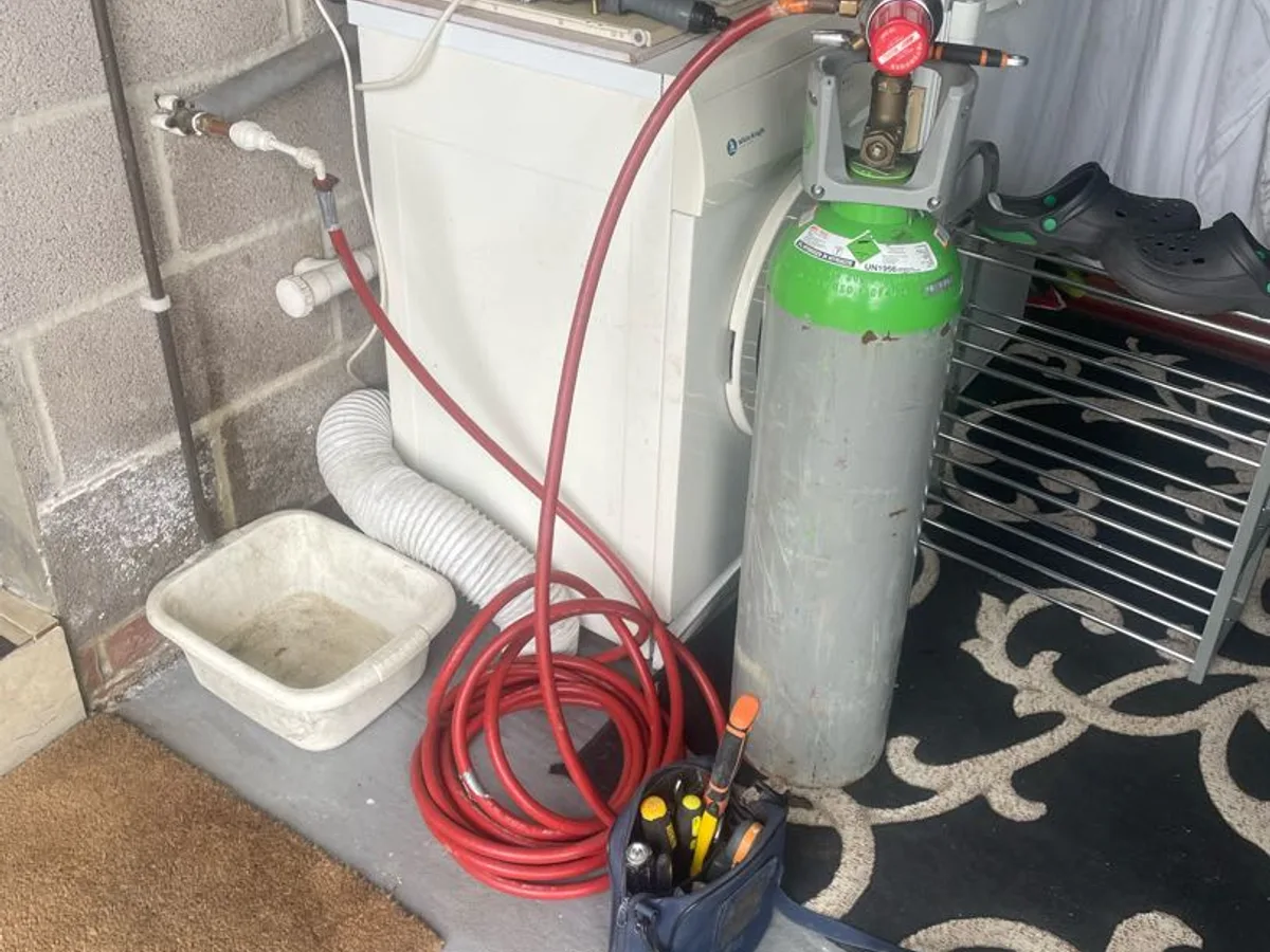 tracer gas cylinder connected via hose to garden tap in garage during leak detection