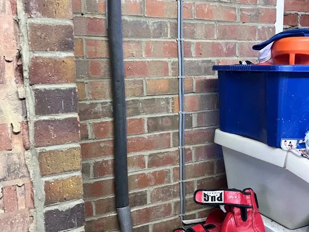 new hot water pipe clipped to external garage brick wall during repair in progress