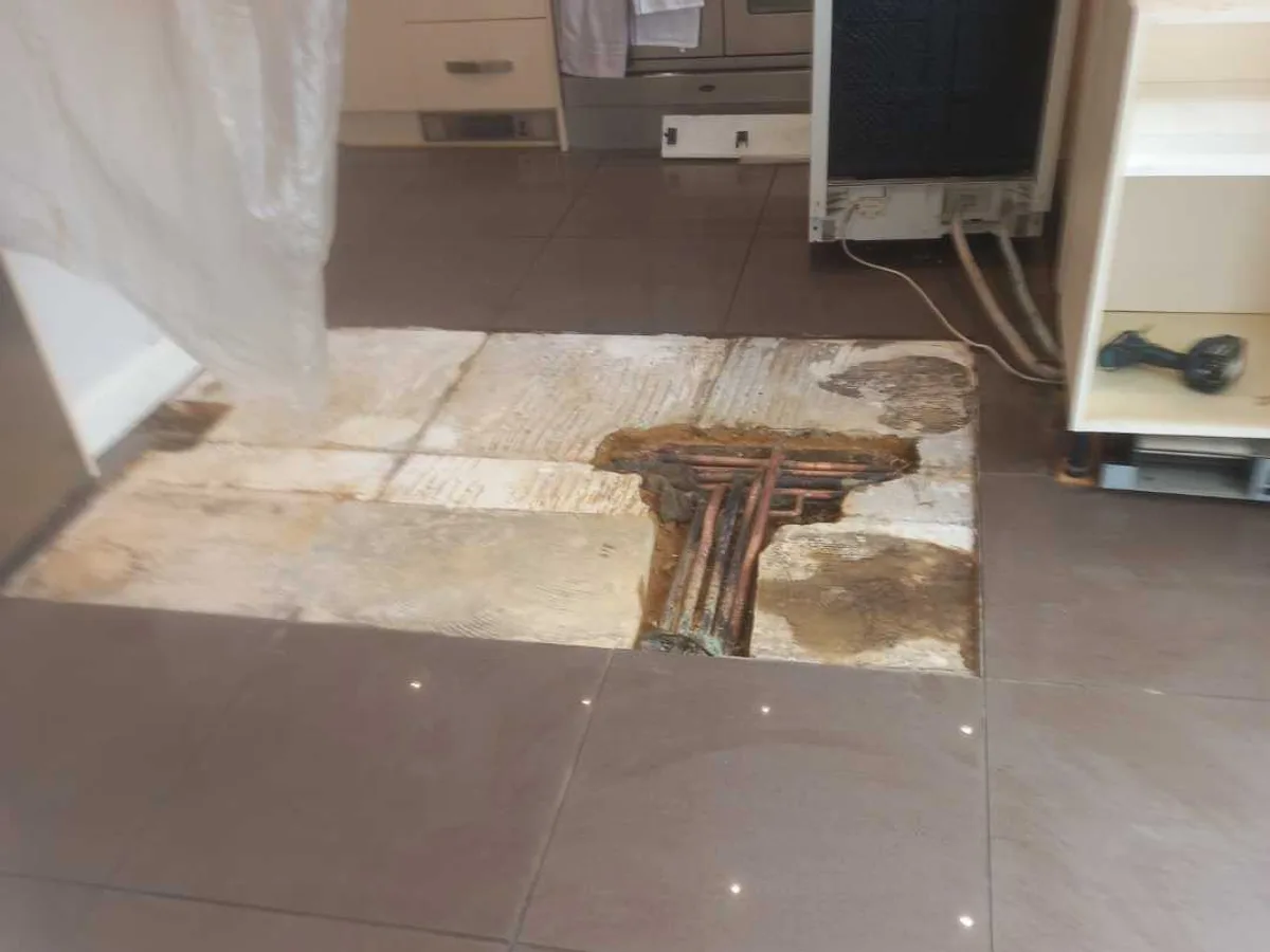 kitchen floor after works completed showing backfilled excavation with repaired pipework exposed prior to tiling