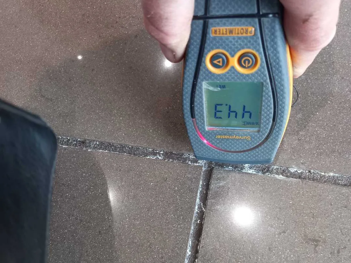 moisture meter reading high levels on kitchen floor tile grout during leak detection survey