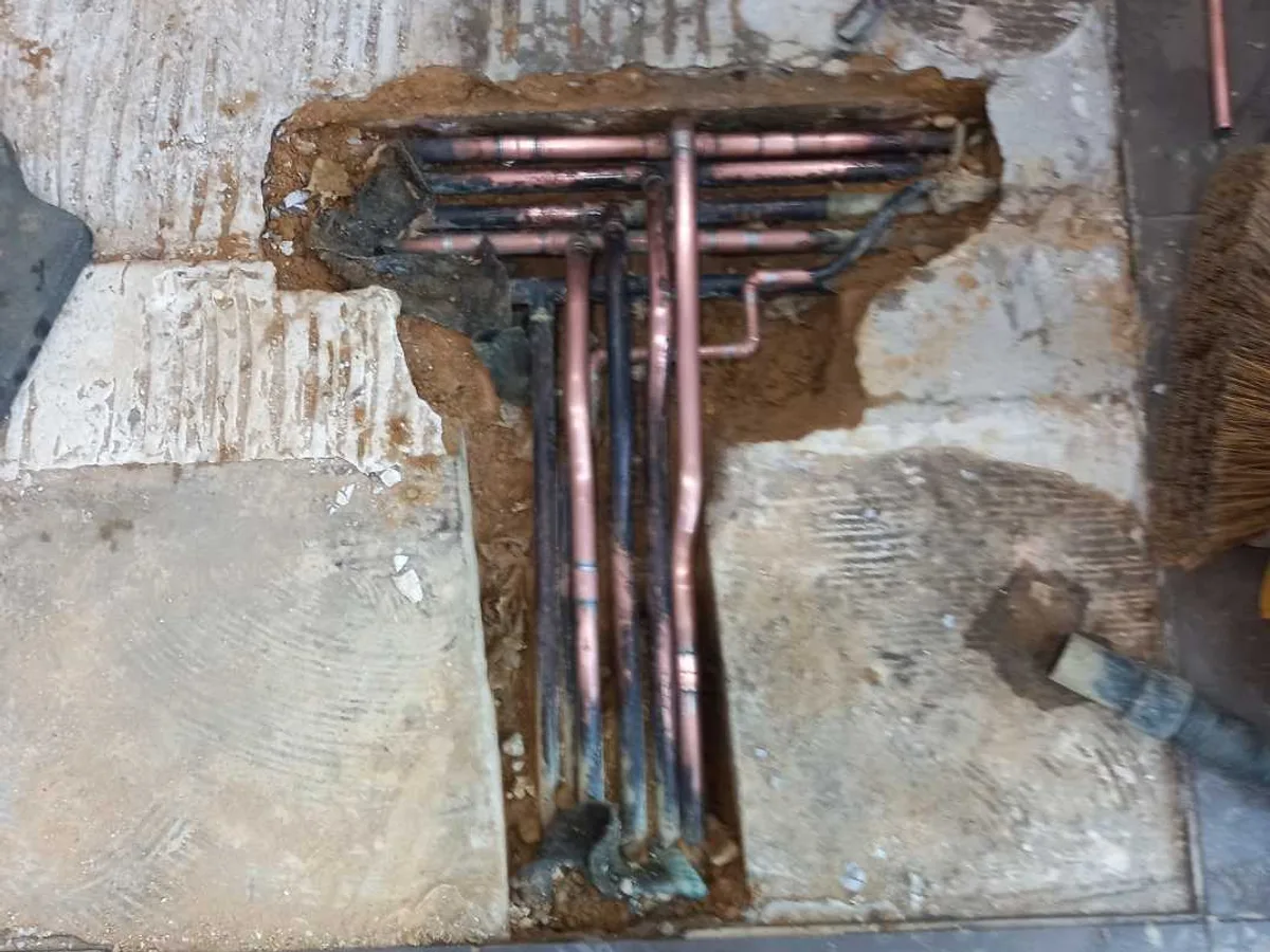 new copper pipework with compression fittings laid in floor trench repair in progress