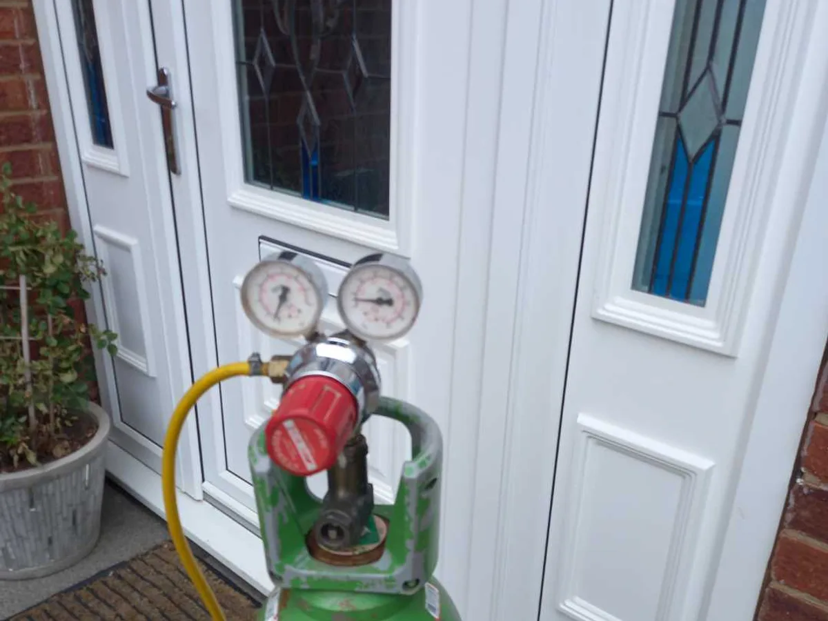 tracer gas cylinder with dual-gauge regulator and yellow hose in use during investigation