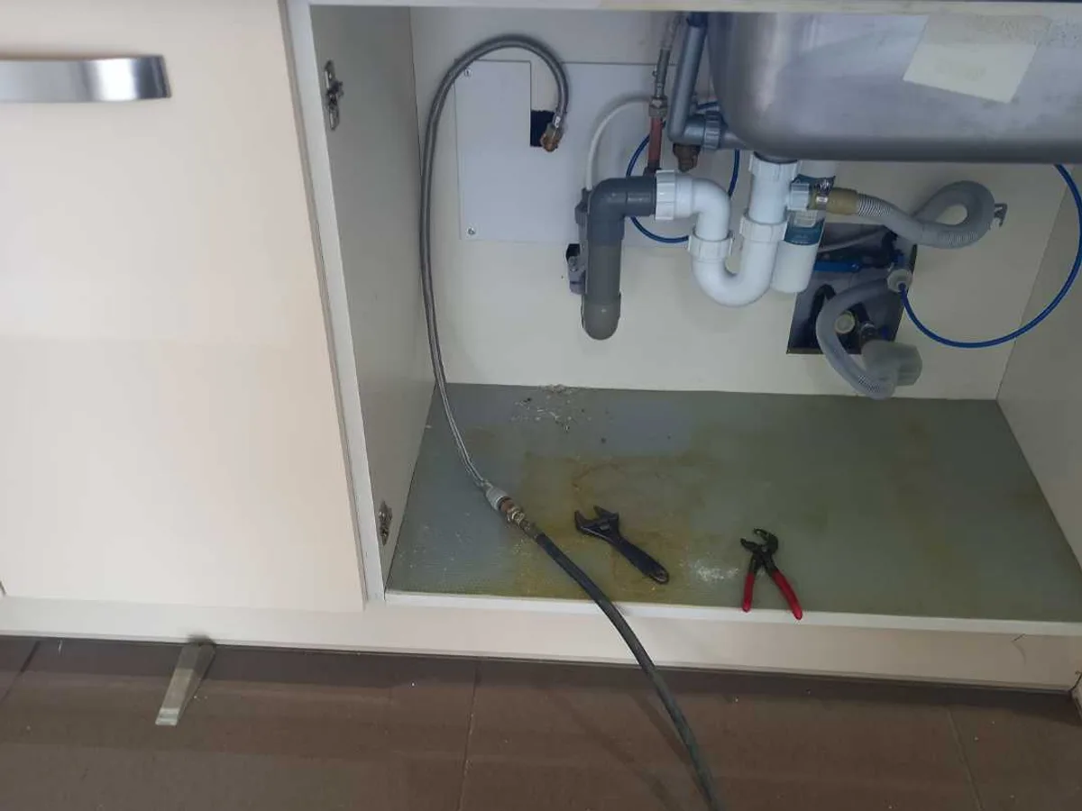 under-sink kitchen unit with tracer gas hose inserted during leak detection