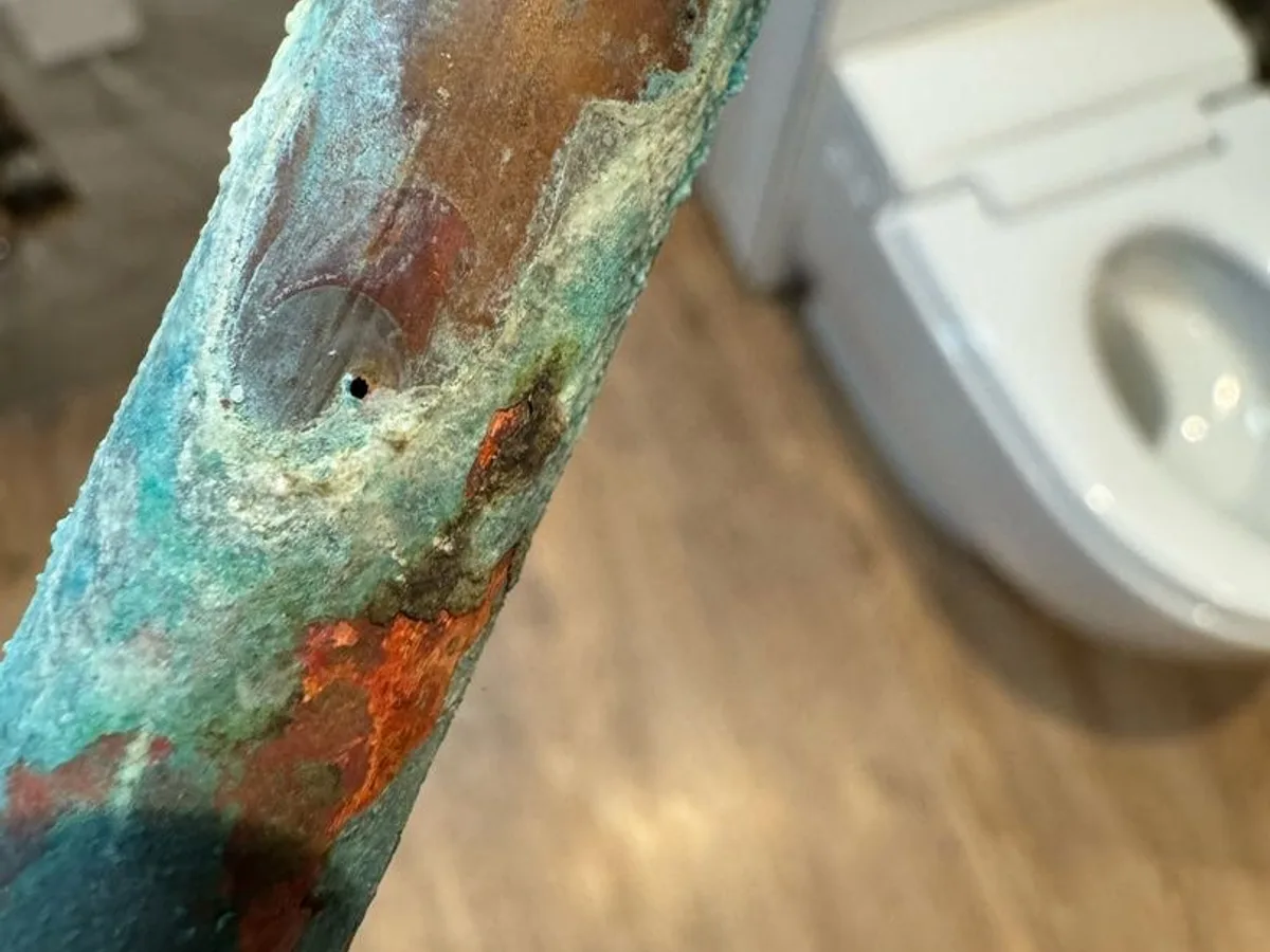leak found at pinhole on removed section of heavily corroded copper hot water pipe