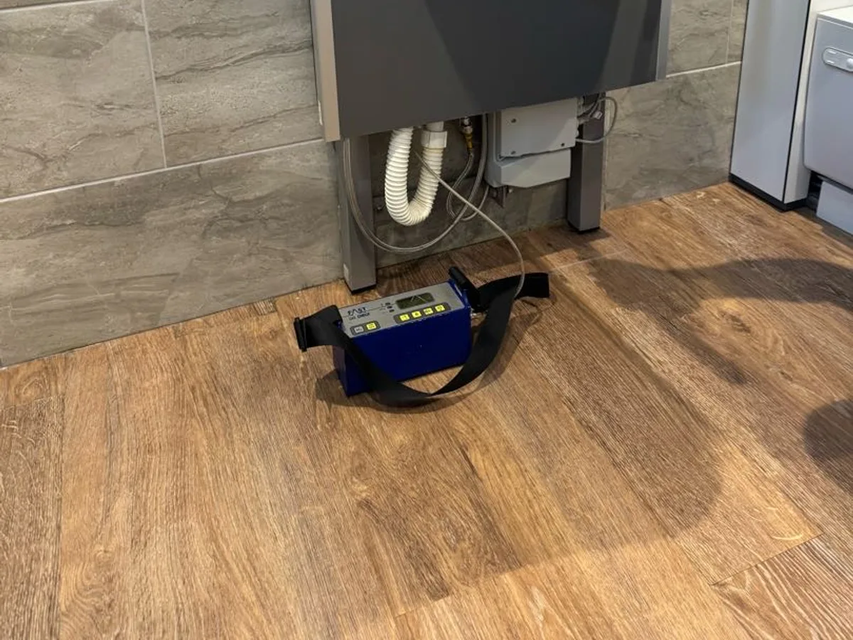 tracer gas detector unit connected beneath disability-adapted sink during leak detection investigation
