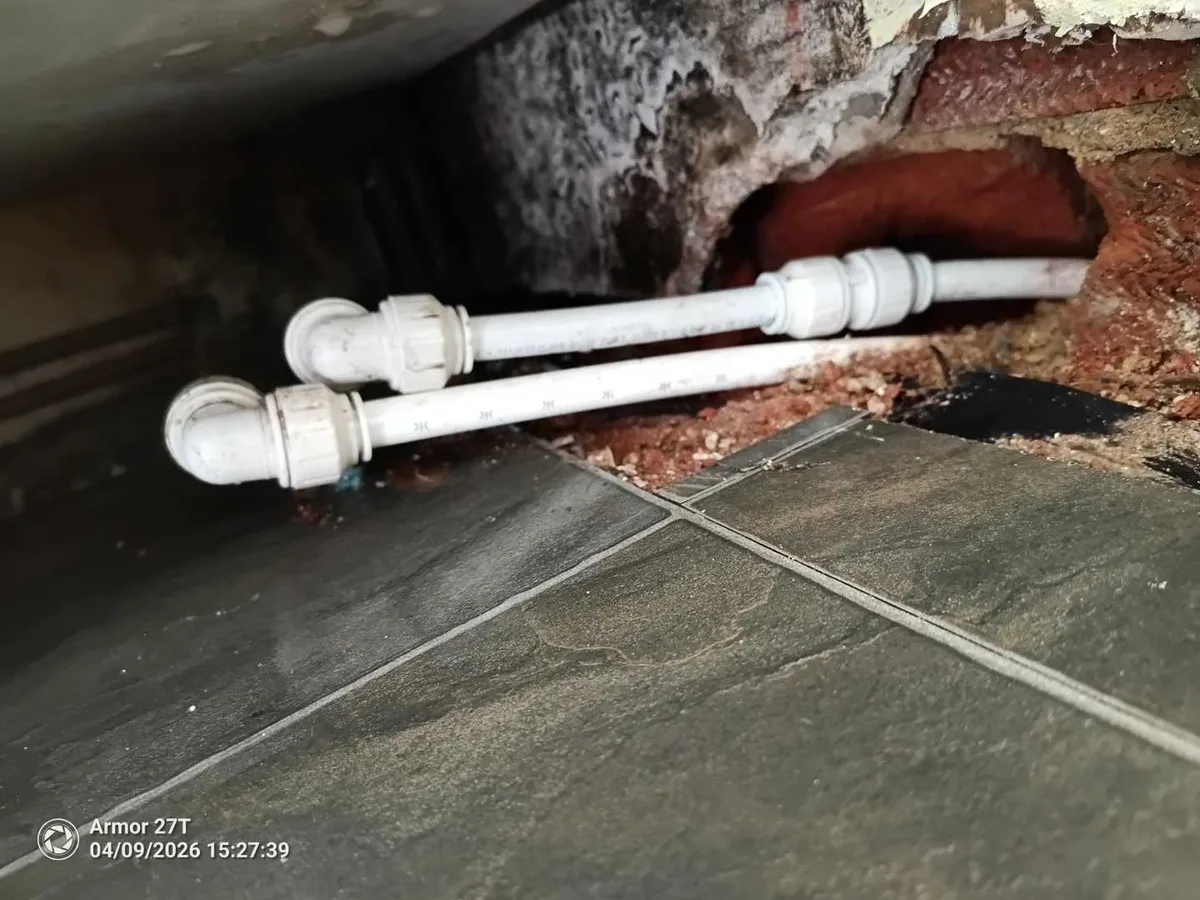 new 15mm pipe with compression fittings routed through exposed brick wall as repair completed