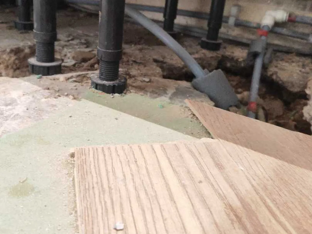 repair in progress with new flexible push-fit pipework routed beneath kitchen units through excavated screed