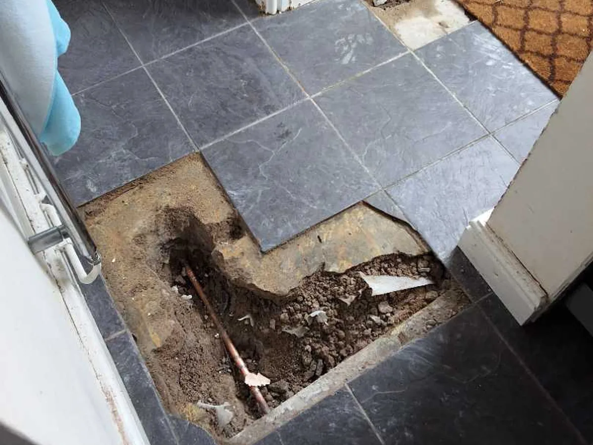 hallway slate floor tiles reinstated after repair to buried hot water supply pipe