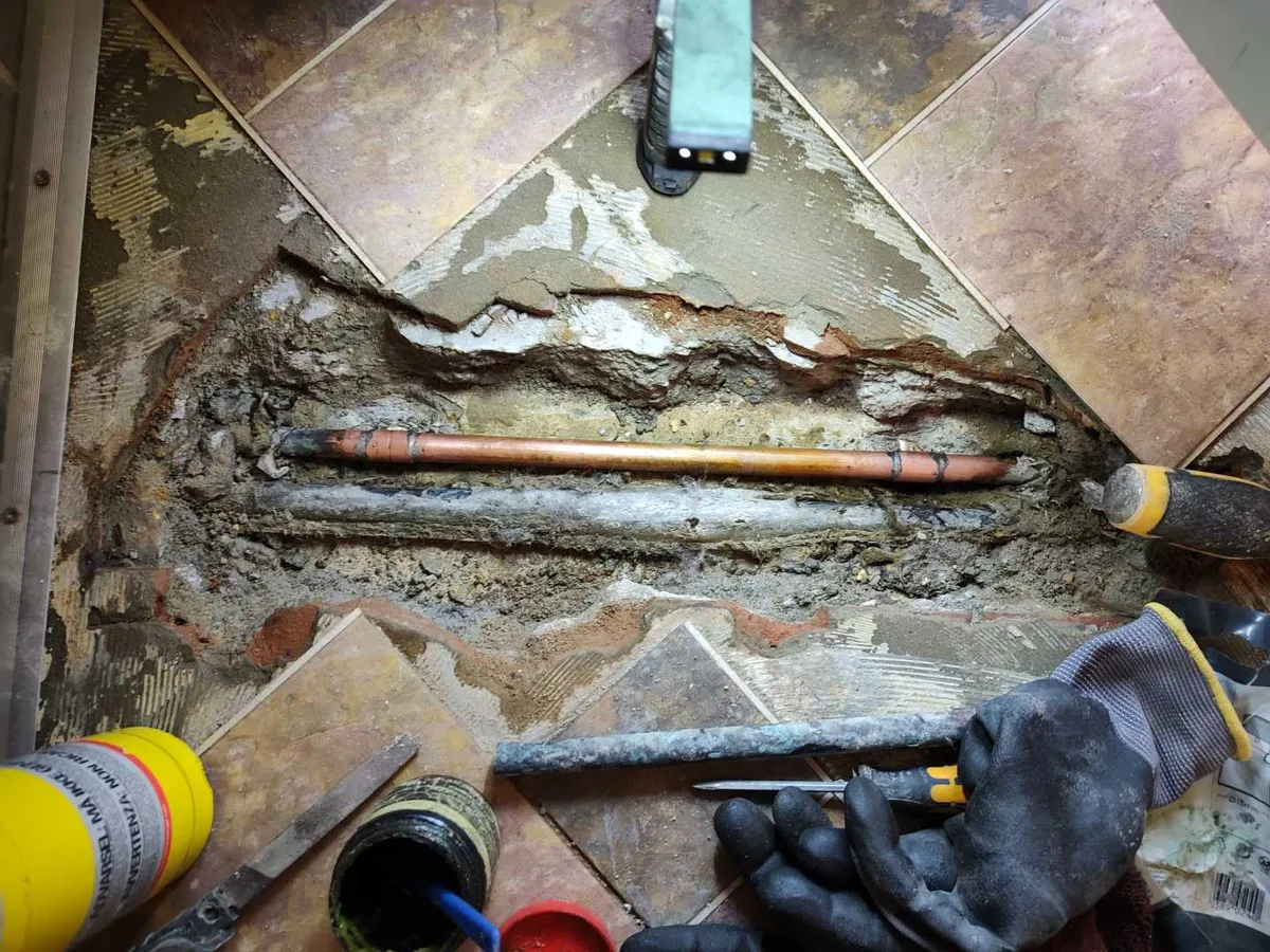 leak located at corroded 15mm copper pipe exposed beneath lobby floor tiles