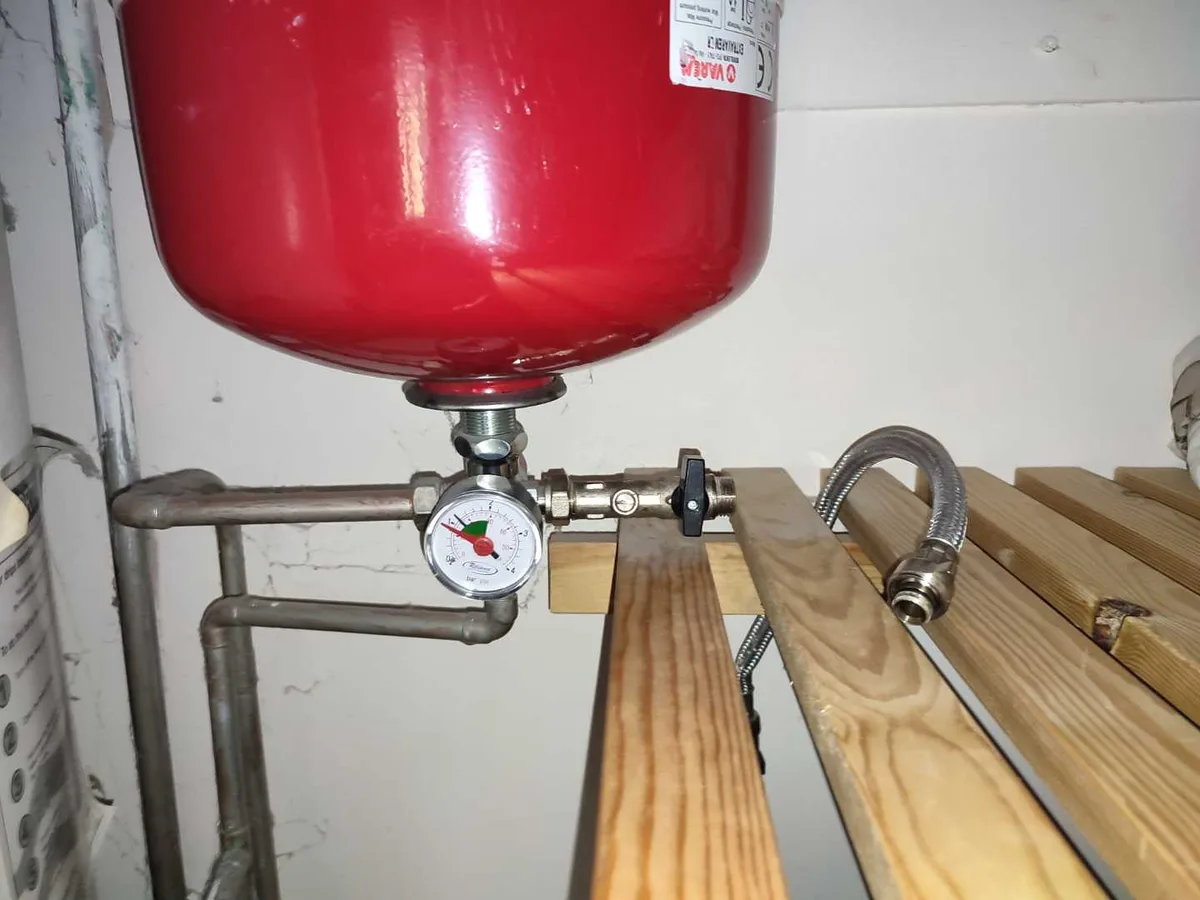 red expansion vessel and pressure gauge on heating system pipework in use during investigation