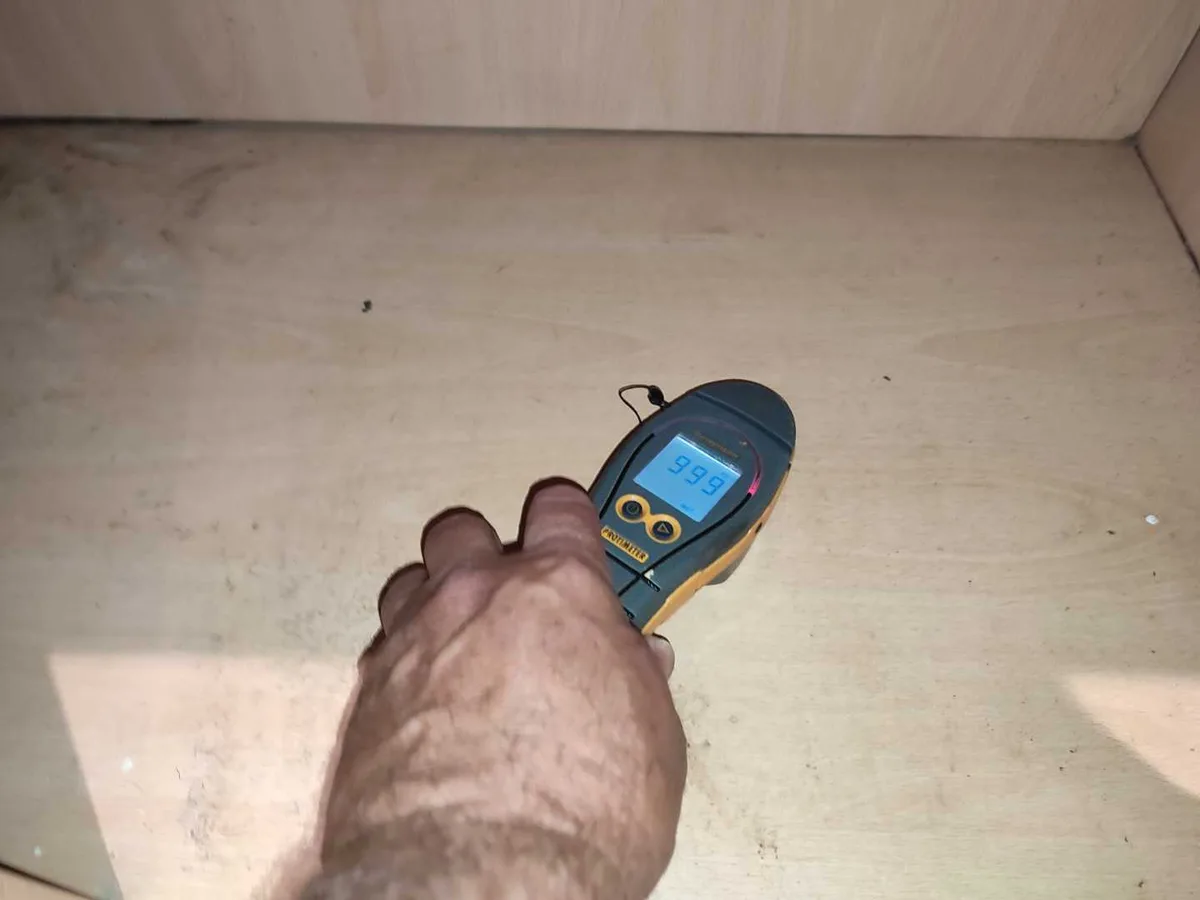 moisture meter reading 99.9 on kitchen cupboard base board during leak detection