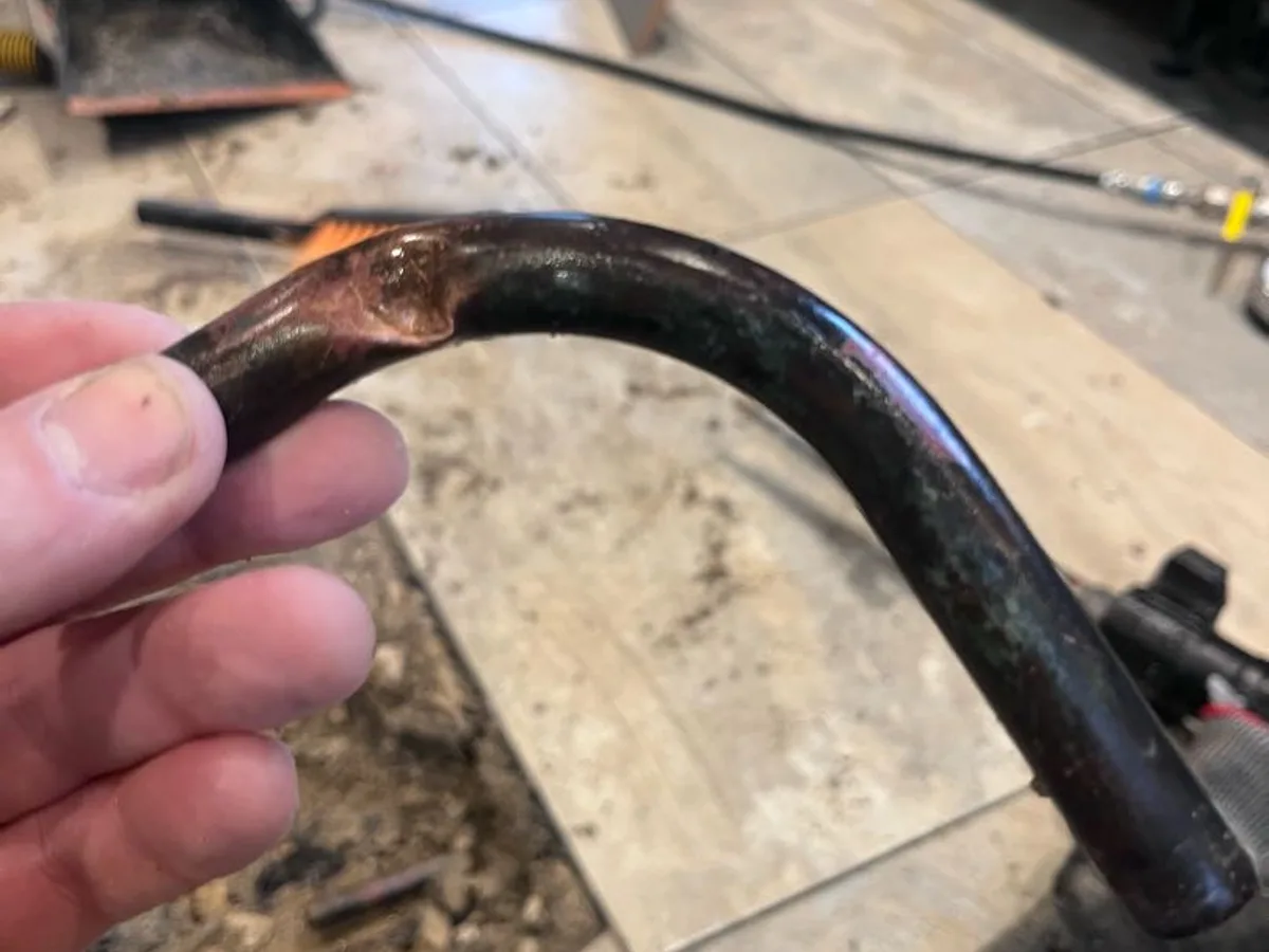 heavily corroded copper pipe bend removed from screed after repair completed