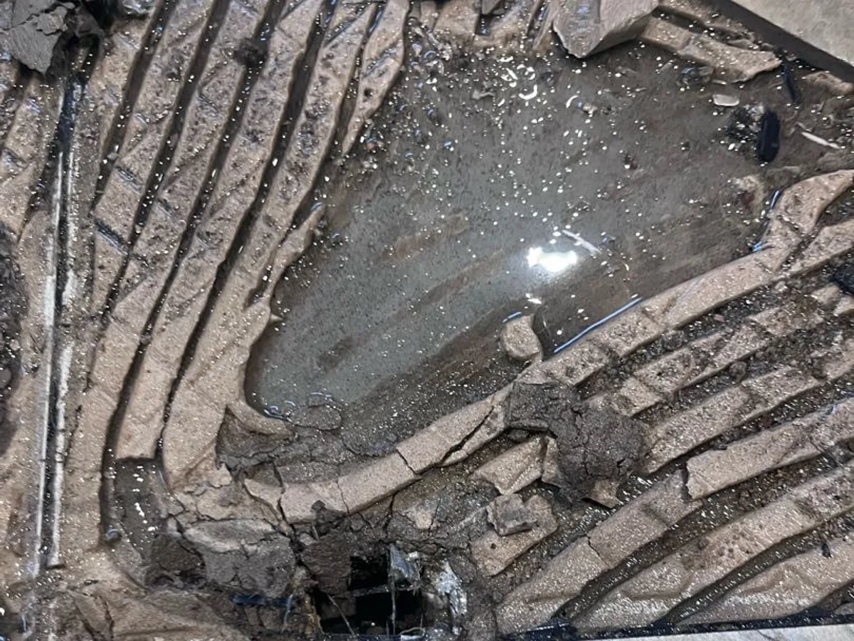 leak located beneath broken kitchen floor tiles with water pooling in concrete screed — leak located at