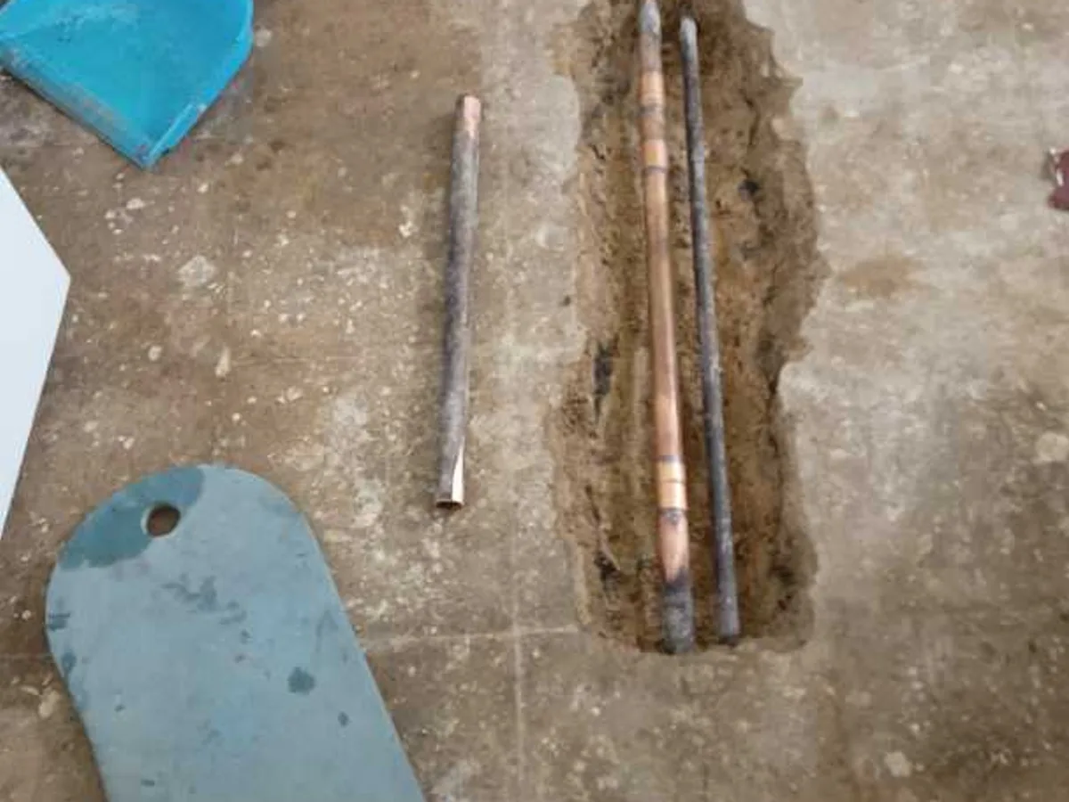 new copper pipe section laid in open floor trench repair in progress on hot feed pipework