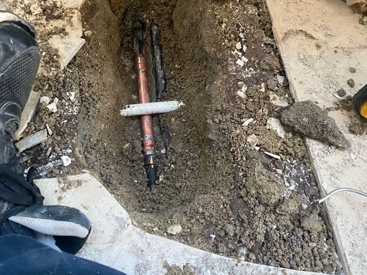 leak found at corroded copper pipe and joint exposed in excavated trench below kitchen screed