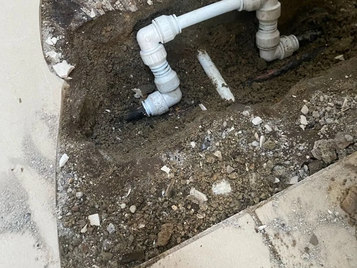 new plastic push-fit elbows and pipe installed in floor trench as repair completed