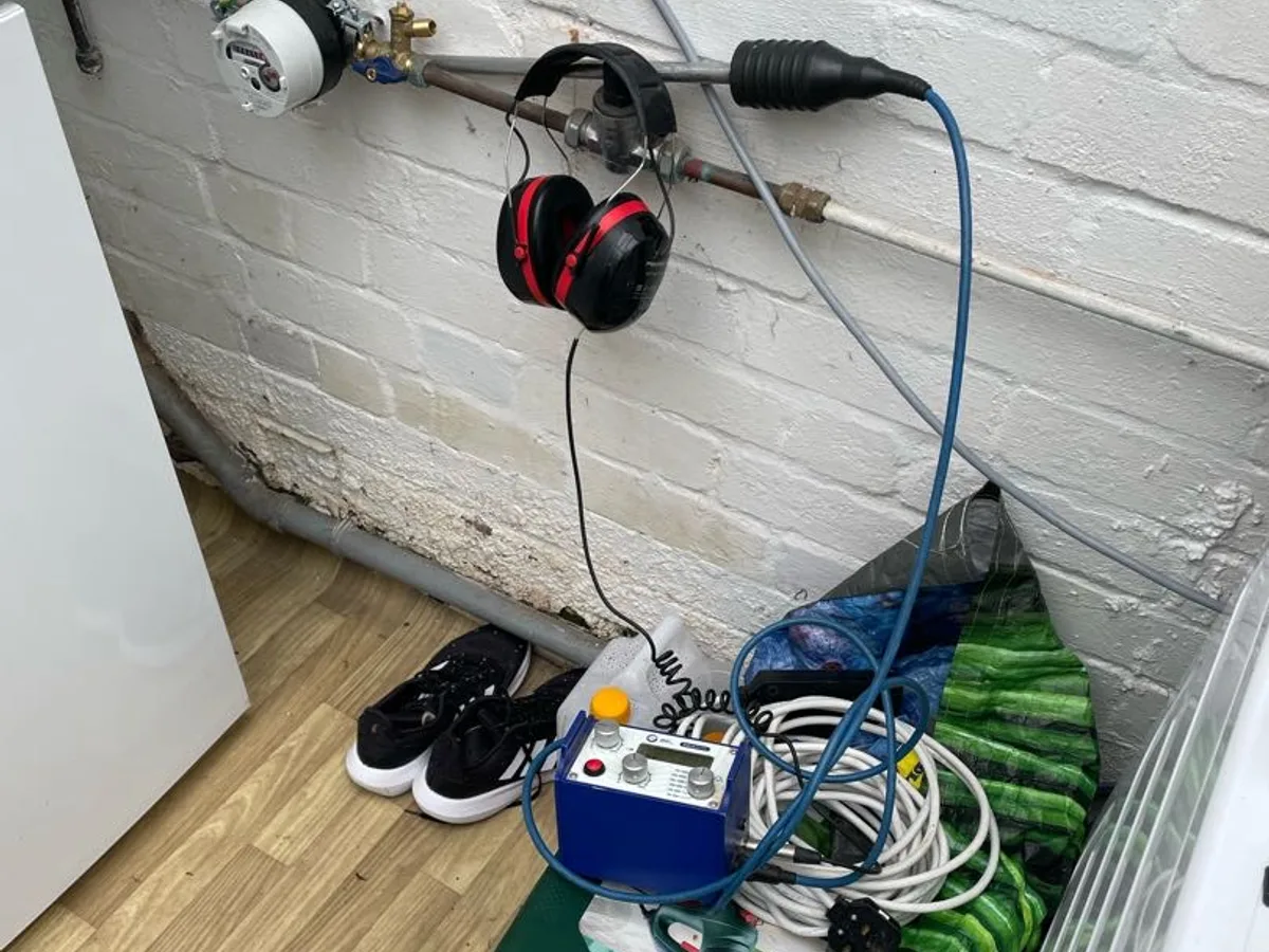 acoustic listening equipment connected to pipework on brick wall during leak detection