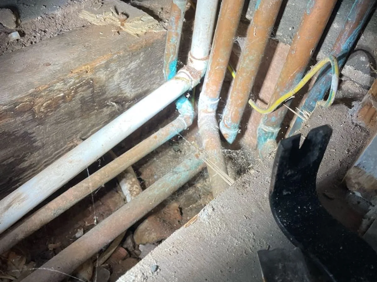 fault exposed at boiler cupboard floor with wet corroded pipework visible after boards lifted