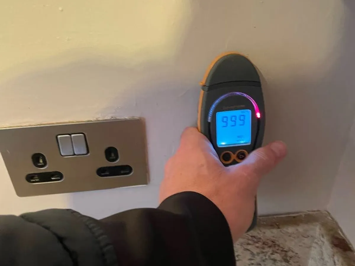 moisture meter showing maximum reading of 999 on kitchen wall during leak detection