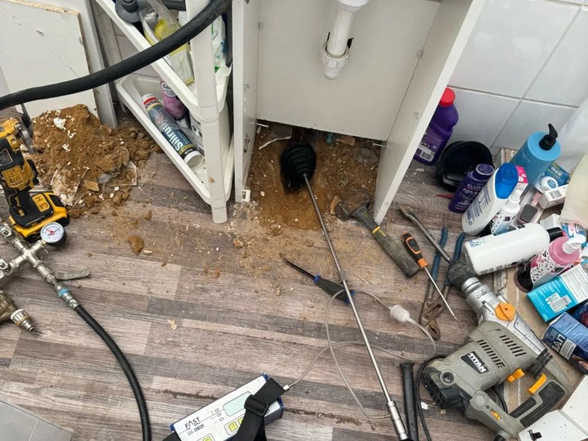 floor excavated beneath toilet basin cabinet during investigation — during leak detection
