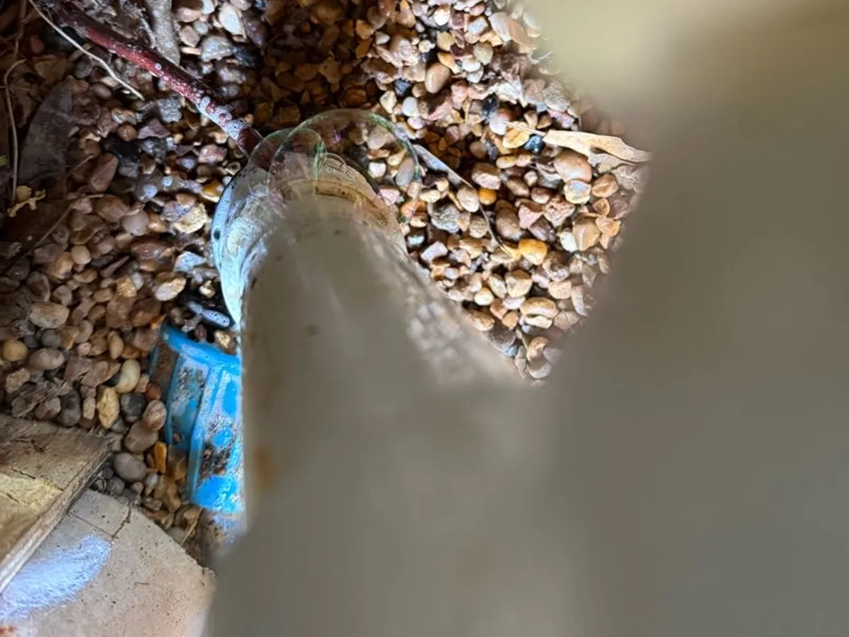 leak located at cracked skimmer pipework surrounded by gravel beneath pool surround