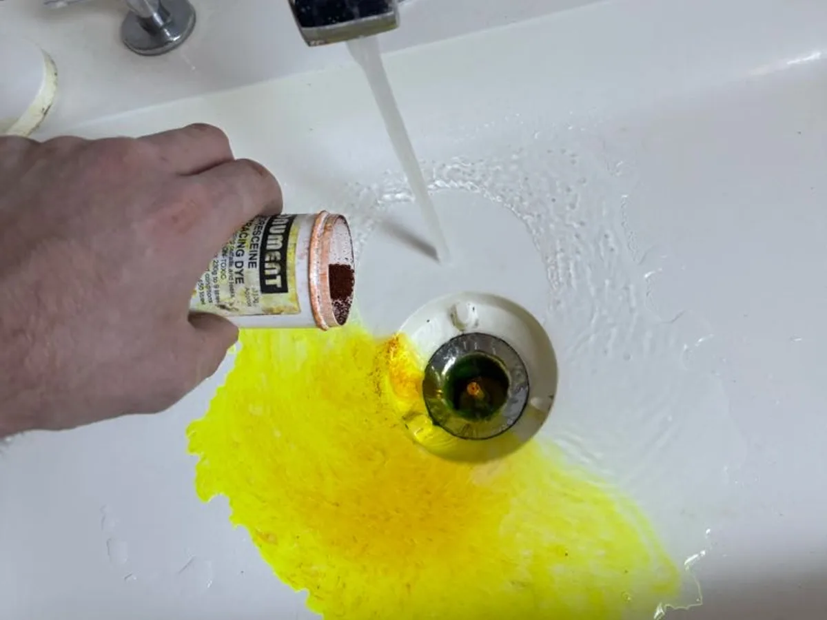 fluorescent dye being added to basin waste during leak detection investigation